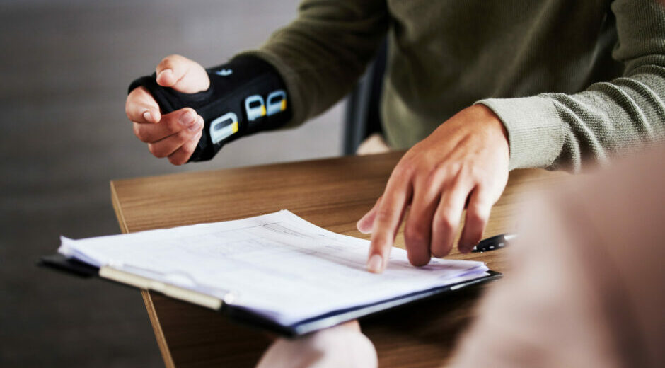 Commentary 12 Injury, compensation and man hands with insurance documents, legal contract and paperwork. Disability, accident and people in lawyer or attorney meeting for advice, agreement or policy report closeup