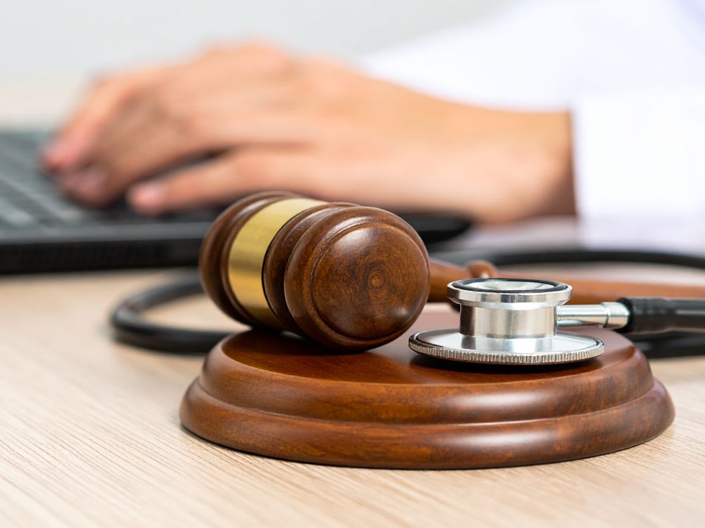Commentary 2 QME doctor with a gavel on their desk typing on a laptop